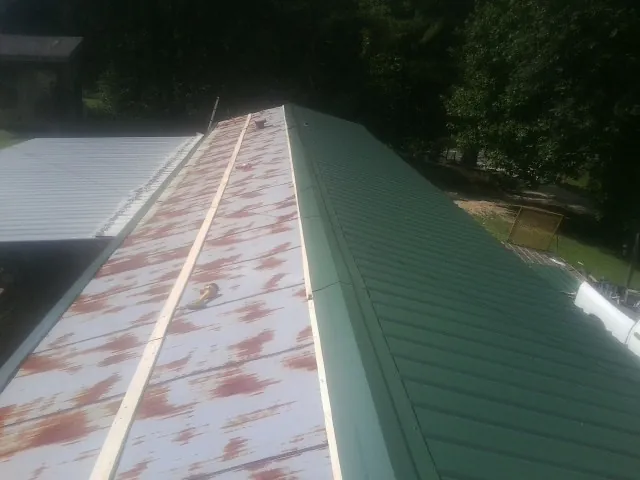Old rusted panels beside newly installed green metal roofing — Wind Damage Roof Repair by Roofing Brothers in Owatonna