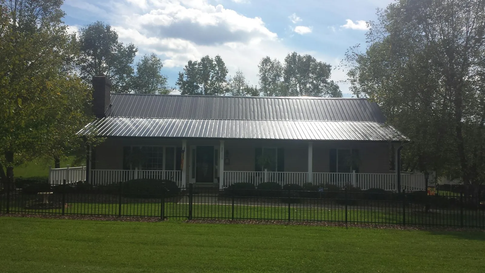 Gray metal roof on a brick ranch with a full width front porch — Gutter Guard Installation work by our crew in Owatonna