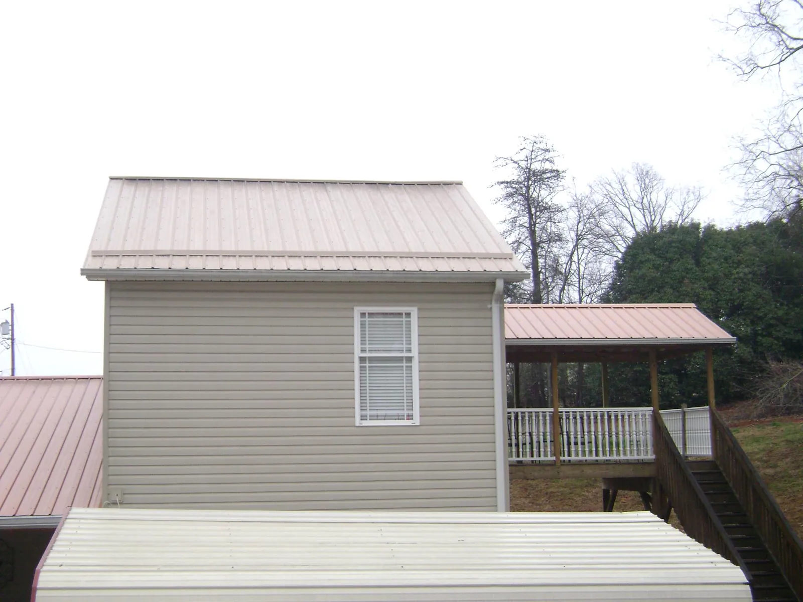 Tan metal roofs on a two story addition and attached porch, from a Roof Replacement job in Owatonna