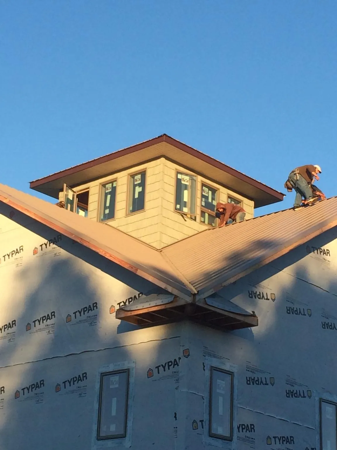 Roofers working around a rooftop cupola on a new metal roof at sunset — Roof Waterproofing in Owatonna by Roofing Brothers